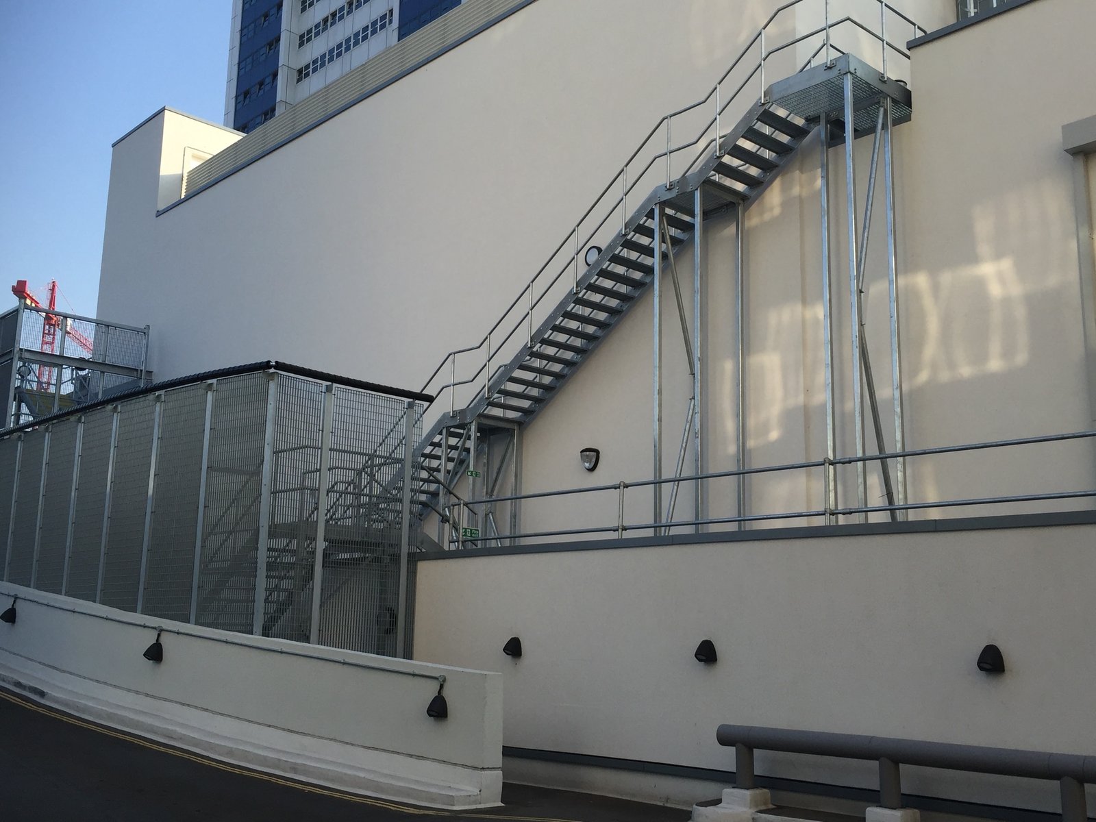 Galvanised steel fire escape staircase with mesh balustrade on a commercial building